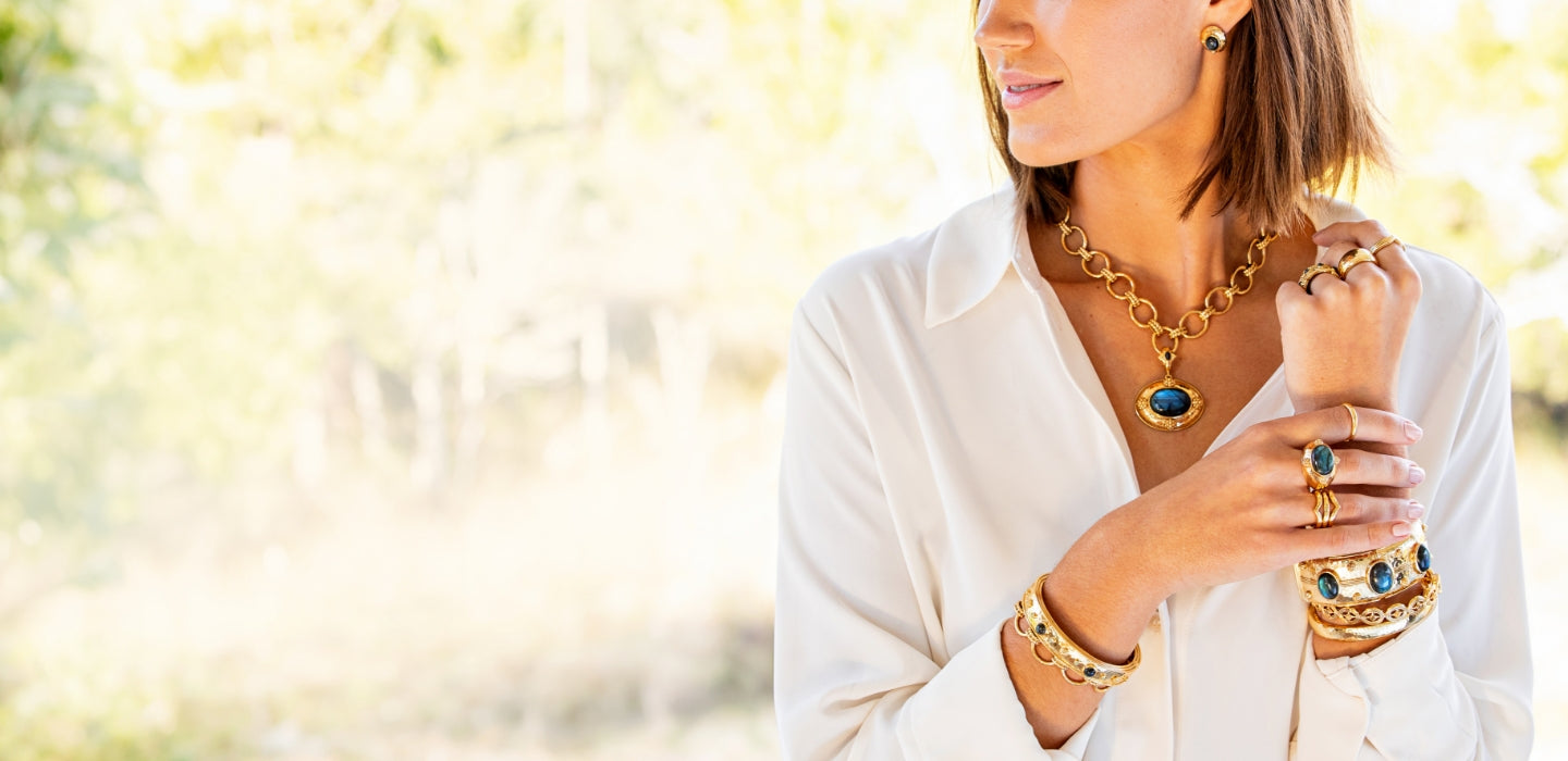Woman wearing gold jewelry with a blurred natural background