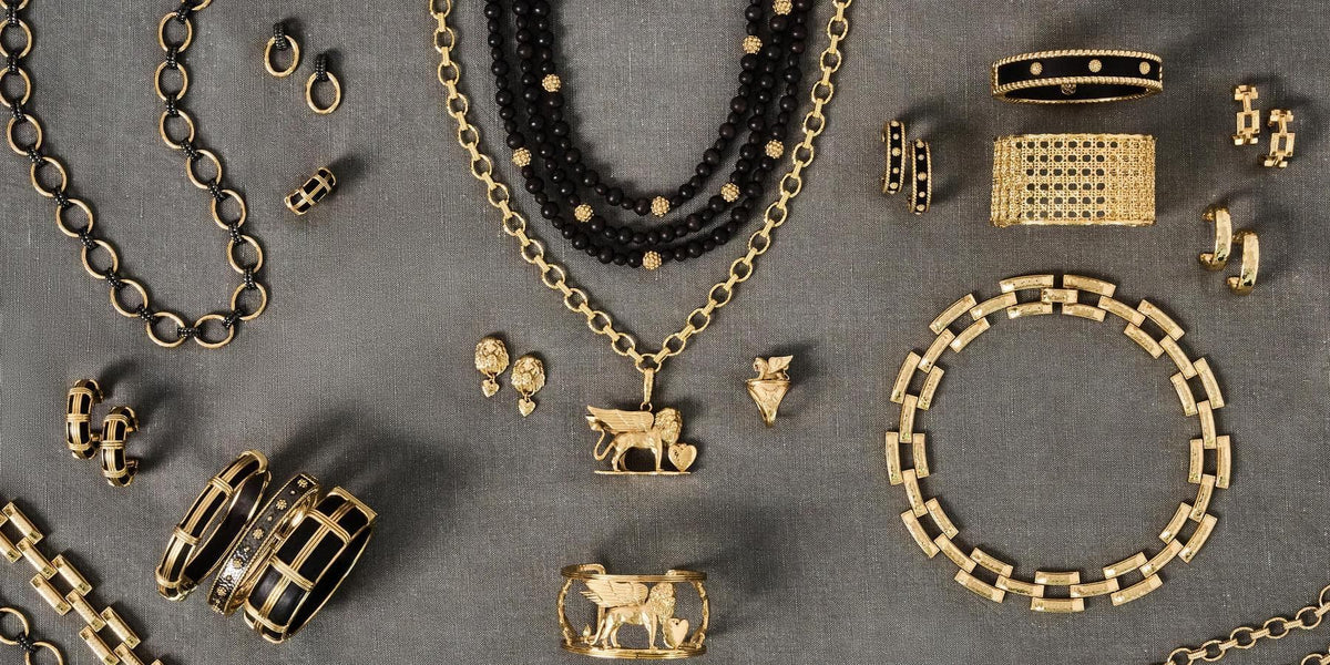 Overheads shot of gold and black jewelry lay down on grey background.