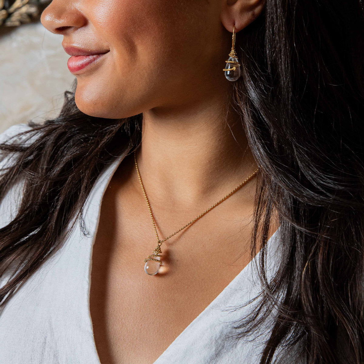 Close-up of a woman wearing a gold necklace and earrings.