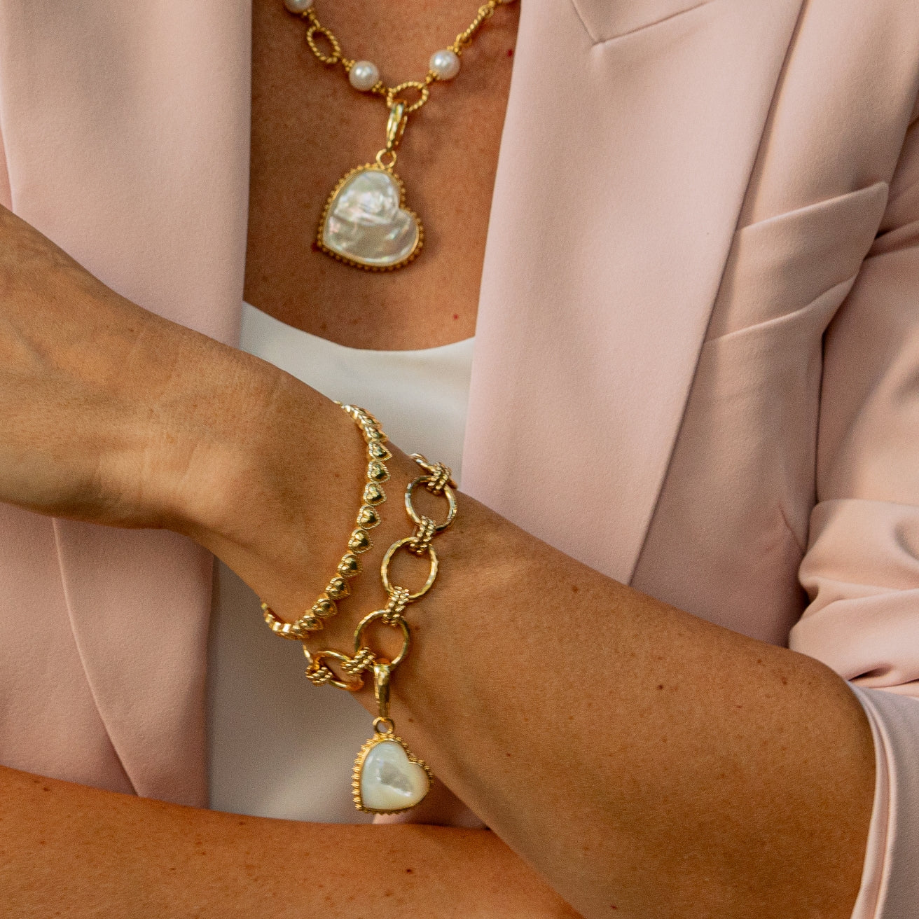 Gold bracelet with a heart-shaped pendant worn on a wrist