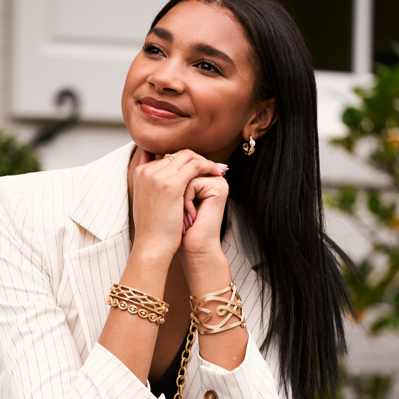 Woman wearing gold jewelry with a blurred outdoor background
