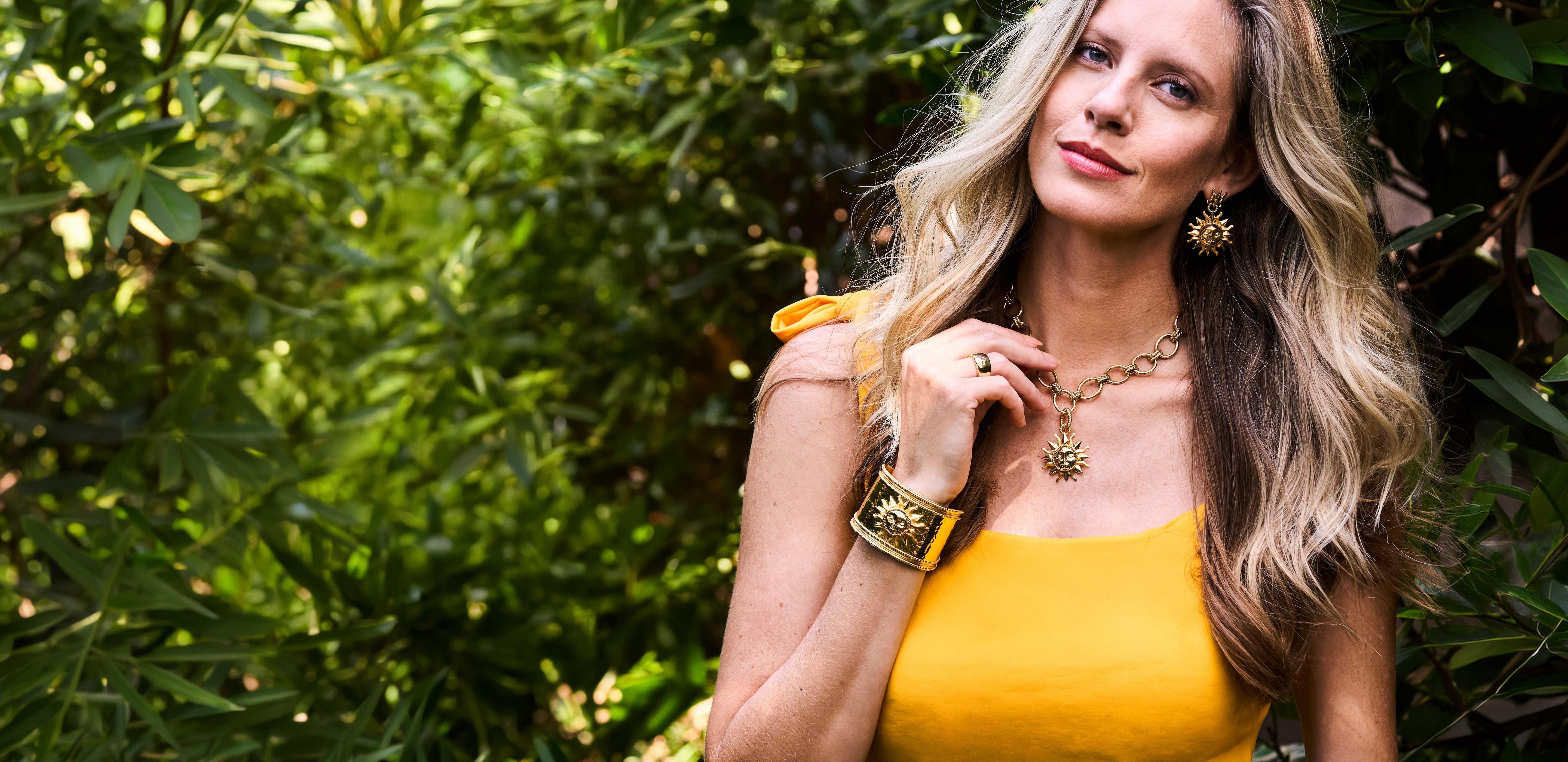 Woman in a yellow dress standing in front of green foliage