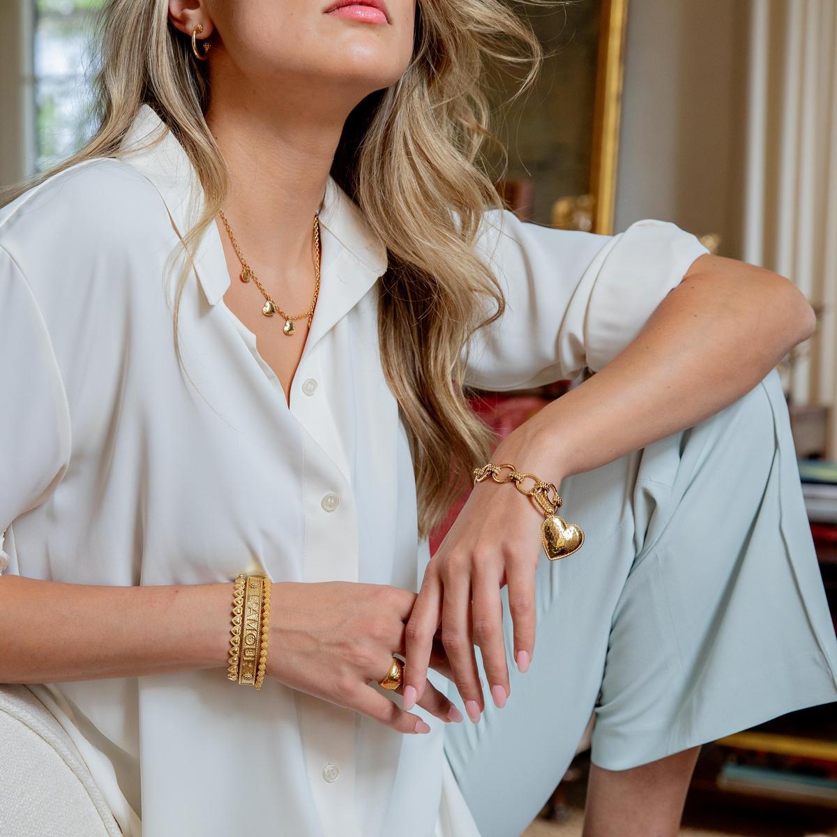 Woman wearing Love gold bracelets, multi-station necklace, and pendant