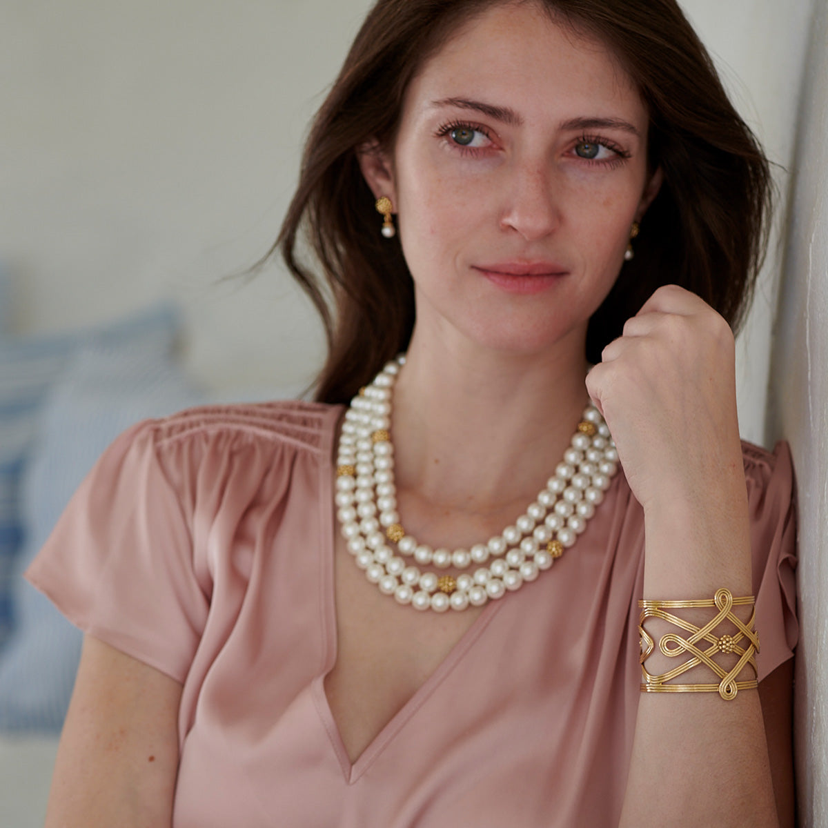 Woman wearing a pearl necklace and gold bracelet indoors