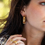 The Greek goddess personifying Earth, Gaia is strong, protective and nurturing. These hand- carved teak earrings are accented with ley-lines of gleaming gold and are a natural neutral that transitions beautifully from casual to formal and day to night. Complete the set with our Gaia Hinged Bangle.