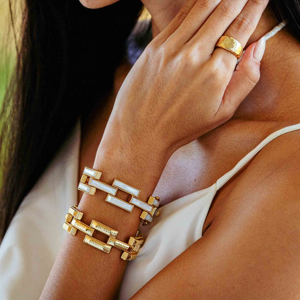 Closeup image showing woman's wrist and hand with a gold bracelet and ring