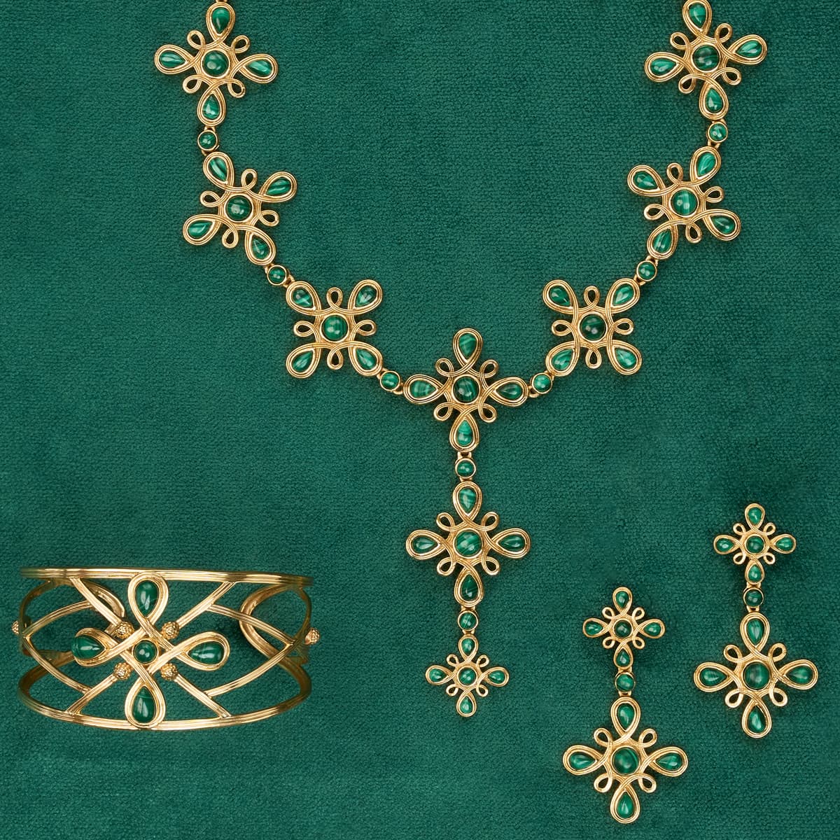 Gold jewelry set with green gemstones on a green background