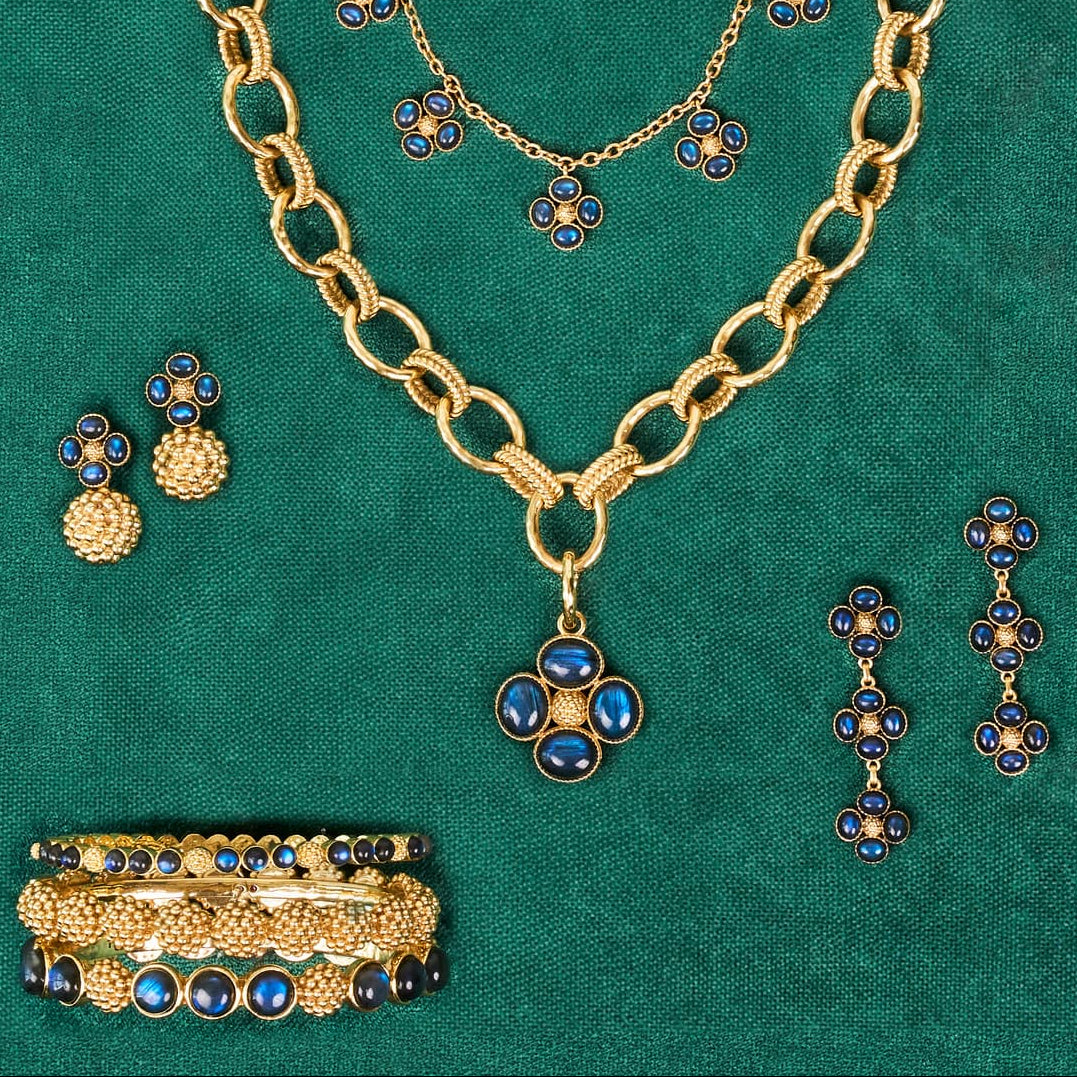 Gold jewelry set with blue stones on a green background