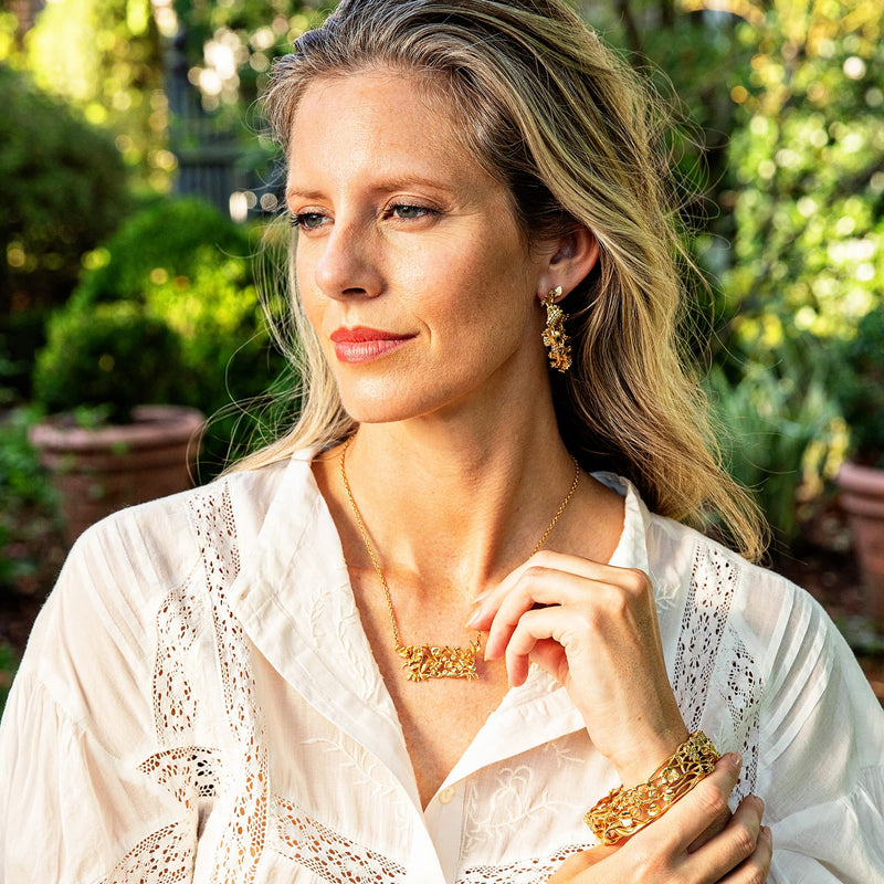 Woman looking off and smiling wearing golden floral jewelry. 