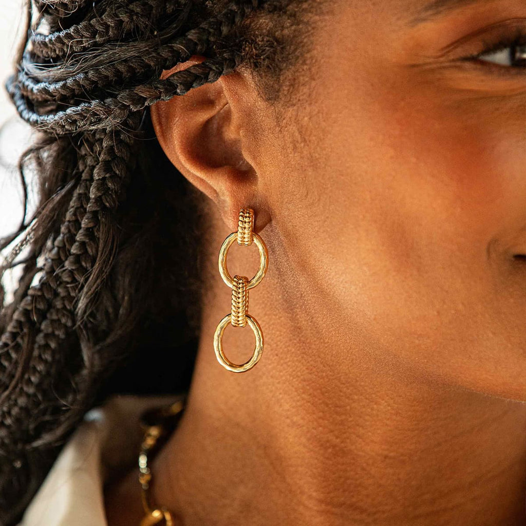 Closeup of woman's ear with golden link earring.