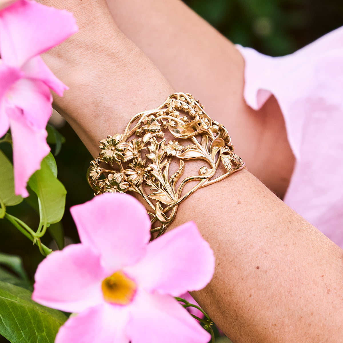 Meadow Walk gold bracelet on woman's wrist with pink flowers around 