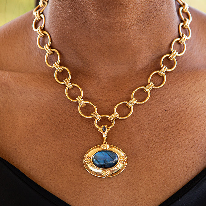 Gold necklace with a blue pendant on a person's neck