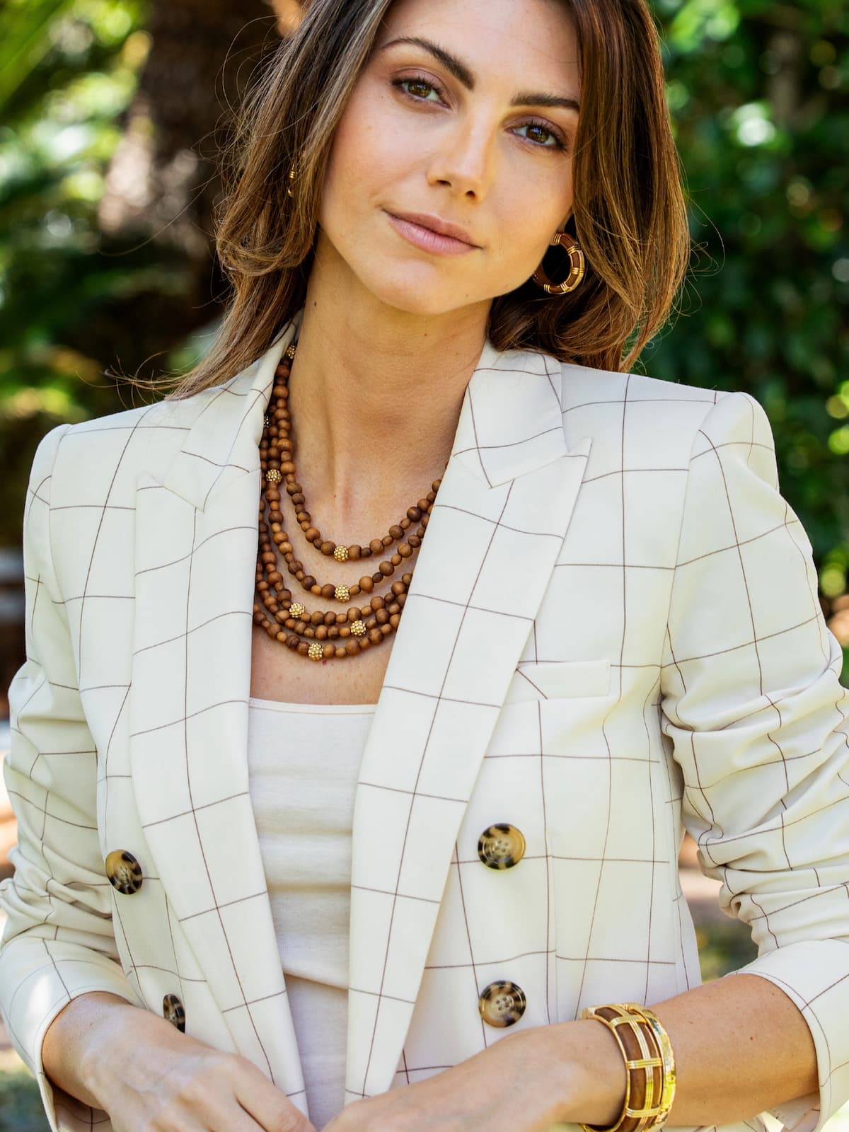 Woman wearing a checkered blazer with a blurred green background