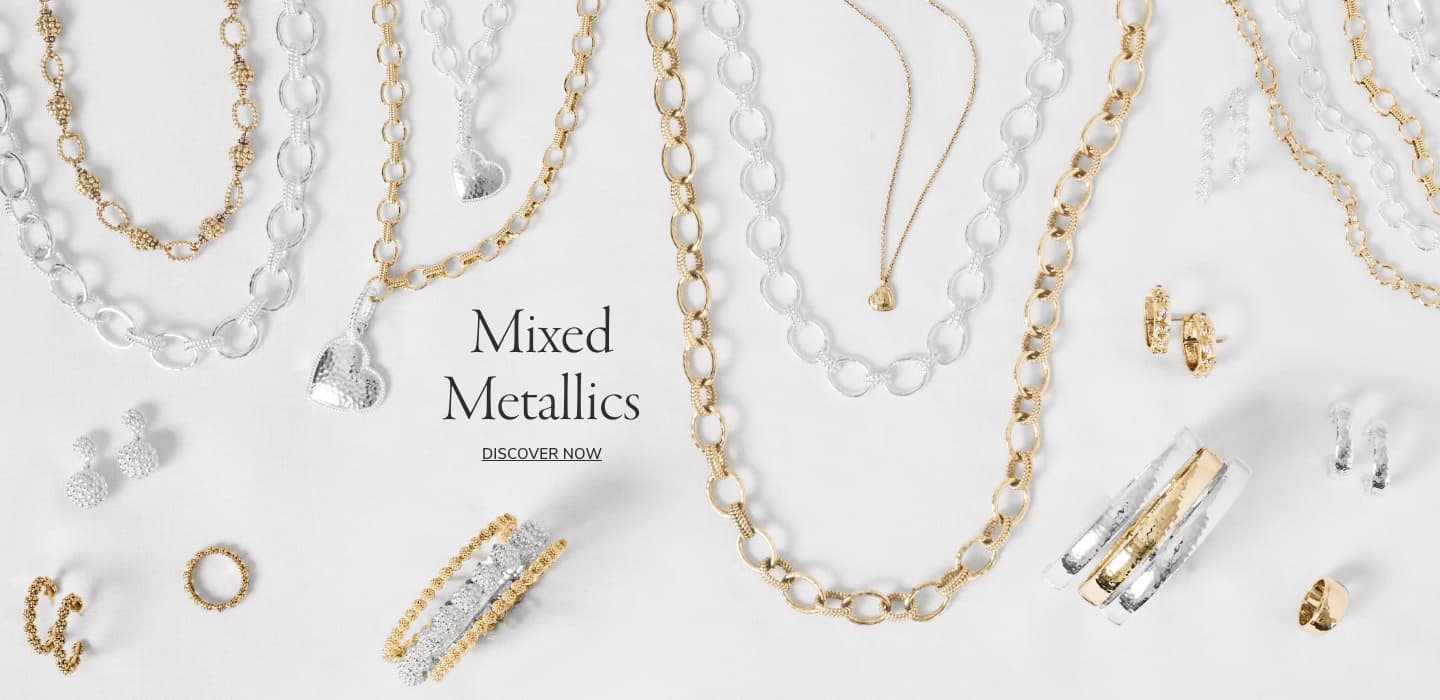 A styled flat-lay of mixed metallic jewelry on a white background, featuring gold and silver chains, rings, earrings, and bracelets with the text 'Mixed Metallics' and 'Discover Now' in the center.