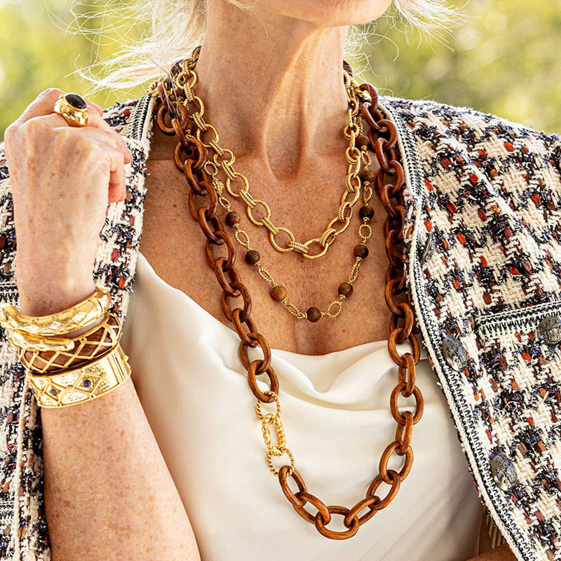 Three link necklaces create the perfect layered look over a white blouse.