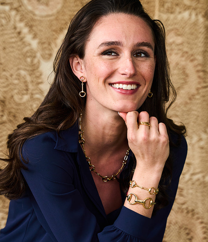 Woman wearing gold jewelry against a beige background