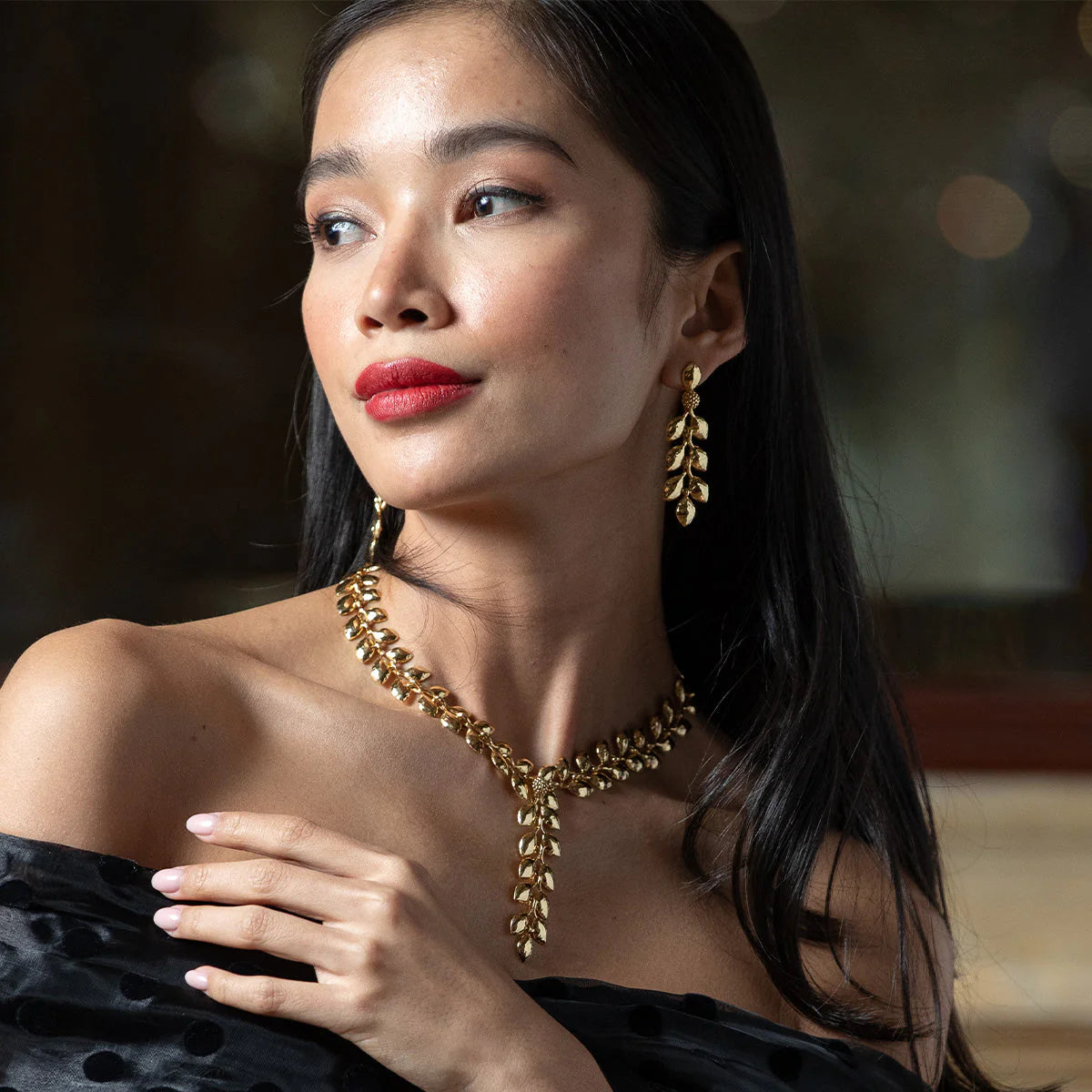 Woman wearing gold jewelry with a blurred background